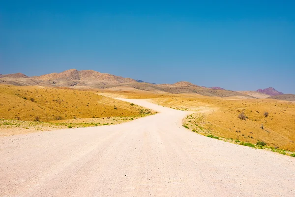 Gravel winding road crossing the colorful Namib desert, in the majestic Namib Naukluft National Park, best travel destination in Namibia, Africa. — Stock Photo, Image