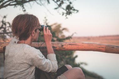 Turist tarafından Binoküler Chobe nehir, Namibya Botsvana sınırında, Afrika yaban hayatı izliyor. Chobe Ulusal Park, ünlü wildlilfe koruma ve lüks seyahat hedef. Tonlu görüntü.