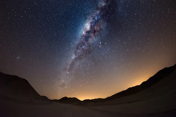 Starry sky and Milky Way arc, with details of its colorful core, outstandingly bright, captured from the Namib desert in Namibia, Africa. The Small Magellanic Cloud on the left hand side.