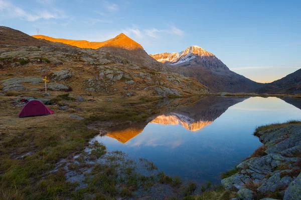 Acampar com tenda perto de lago de alta altitude nos Alpes. Reflexão da cordilheira coberta de neve e céu colorido cênico ao pôr-do-sol. Aventura e exploração . — Fotografia de Stock