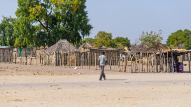 Caprivi, Namibia - August 20, 2016: Poor man walking on the roadside in the rural Caprivi Strip, the most populated region in Namibia, Africa. clipart