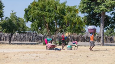 Caprivi, Namibia - August 20, 2016: Poor women walking on the roadside in the rural Caprivi Strip, the most populated region in Namibia, Africa. clipart