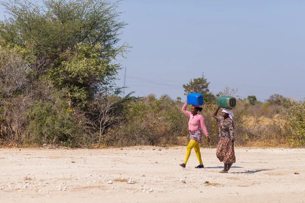 Caprivi, Namibia - 20 de agosto de 2016: Mujeres pobres caminando en la carretera en la franja rural de Caprivi, la región más poblada de Namibia, África . — Foto de Stock