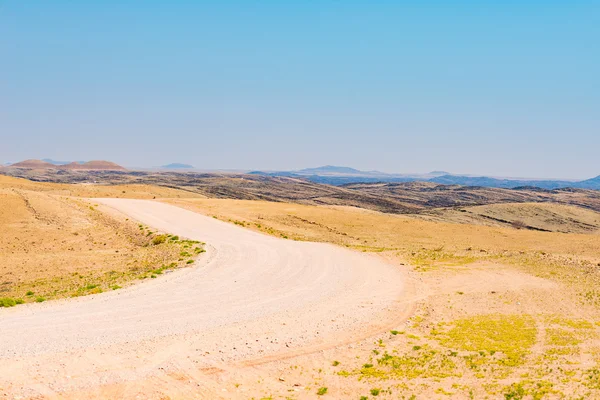 Żwir kręta droga przez kolorowe pustynię Namib, w majestatyczny Park Narodowy Namib Naukluft, najlepiej podróż przeznaczenia w Namibia, Afryka. — Zdjęcie stockowe