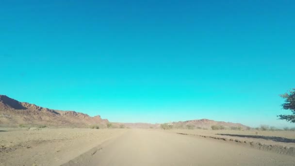 Camino recto de grava que cruza el colorido desierto de Namib, en el majestuoso Parque Nacional Namib Naukluft, el mejor destino de viaje en Namibia, África . — Vídeo de stock