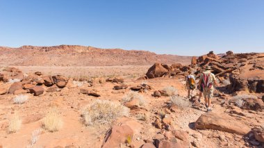 Twyfelfontein, Namibya - 27 Ağustos 2016: Twyfelfontein, dünya mirası rock gravür Damaraland, Namibia, çölde yürüyen turist grup. Kavramı macera ve keşif içinde 