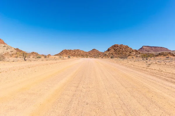 Camino de grava 4x4 que cruza el colorido desierto en Twyfelfontein, en el majestuoso Damaraland Brandberg, destino turístico escénico en Namibia, África . — Foto de Stock