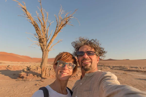 Pareja caucásica adulta tomando selfie en Sossusvlei en el desierto de Namib, Parque Nacional de Namib Naukluft, principal destino de viaje en Namibia, África . — Foto de Stock