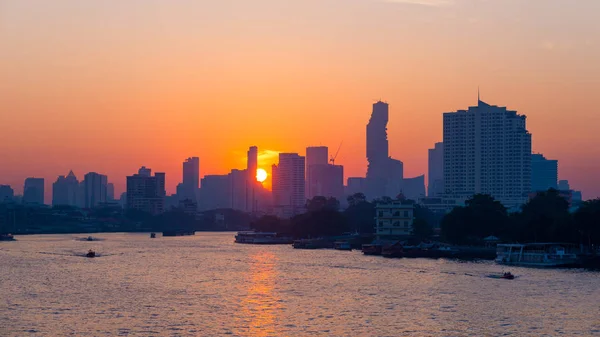 Sunrise over the scenic skyline at Bangkok, Thailand, viewed in backlight at sunrise with orange red clear sky. Boats cruising on the Chao Phraya River. — Stock Photo, Image