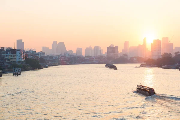 Sunrise over the scenic skyline at Bangkok, Thailand, viewed in backlight at sunrise with orange red clear sky. Boats cruising on the Chao Phraya River. — Stock Photo, Image