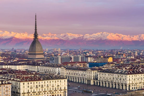 Torino (Torino, Italia): paesaggio urbano all'alba con dettagli della Mole Antonelliana che sovrasta la città. Scenica luce colorata sulle Alpi innevate sullo sfondo . Fotografia Stock