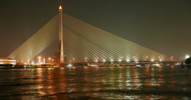 Gece karanlığında, Bangkok, Tayland, Thailand Chao Praya Nehri üzerinde seyir tekneler. Doğal ışıklı köprü içinde belgili tanımlık geçmiş. Zaman atlamalı.