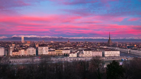 Torino (Turim, Itália): paisagem urbana expansiva ao entardecer com luz colorida cênica sobre os Alpes cobertos de neve no fundo . — Fotografia de Stock