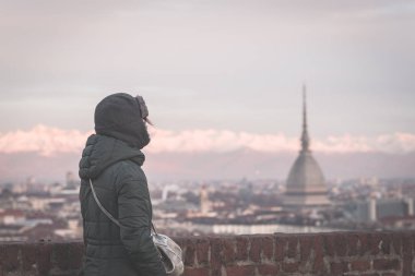 Panoramik manzaralı bir balkon yukarıdaki Torino (Turin, İtalya) bakarak turist. Kış saati, karlı Alps içinde belgili tanımlık geçmiş. Seçici odak, vintage tarzı, görüntü tonda.