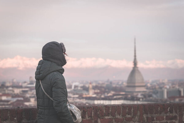 Tourist looking at panoramic view of Torino (Turin, Italy) from balcony above. Winter time, snowcapped Alps in the background. Selective focus, vintage style, toned image.