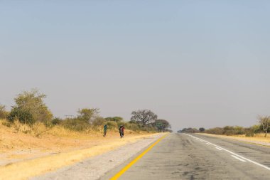 Afrika, Namibya 'nın en kalabalık bölgesi olan Caprivi Bulvarı' nda yol kenarında yürüyen yoksul insanlar.