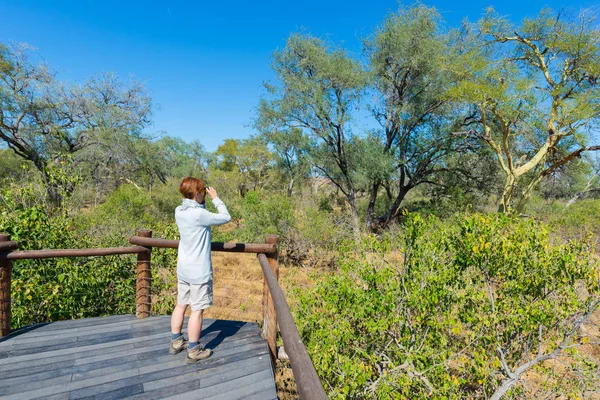 Turista z hlediska nad Olifants river, malebné a malebnou krajinou s volně žijících živočichů v národním parku Kruger, proslulé destinace v Jižní Africe při pohledu na panorama s binokulární. — Stock fotografie