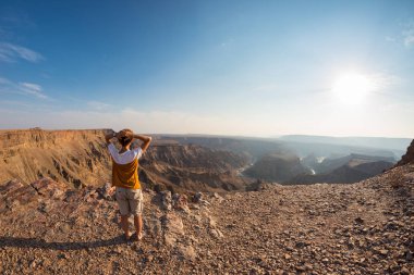 Arkadan görünüş balık River Canyon, doğal seyahat hedef Güney Namibya üzerinden geniş manzaraya bakarak turist. Ultra geniş açılı görünüş yukarıdan.