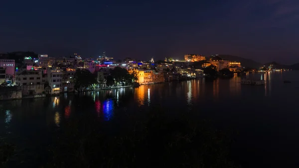 Gloeiende stadsgezicht in Udaipur per nacht. De majestueuze paleis reflecterende stadslichten op Lake Pichola, reis bestemming in Rajasthan, India — Stockfoto