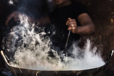 Tanınmayan adam pişirme fatiscent büyük tava ya da wok küçük sokak gıda ahır içinde. Beyaz duman pan dan gelme dışarı el ve kol sadece görünür. Hindistan'da sokak gıda.