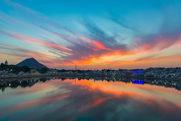 Colorful sky and clouds over Pushkar, Rajasthan, India. Temples, buildings and colors reflecting on the holy water of the lake at sunset. — Stock Photo, Image