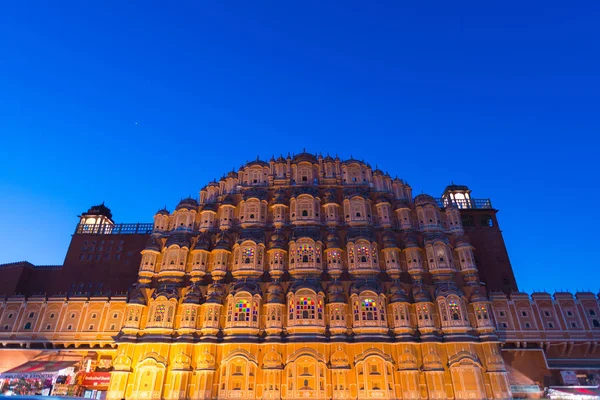 Hawa Mahal het meest iconische symbool op Jaipur, hoofdstad van Rajasthan, India. Schemering tijd met verlichte schilderachtige gevel en blauwe hemel. — Stockfoto