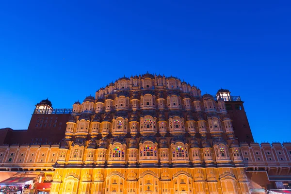 Hawa Mahal het meest iconische symbool op Jaipur, hoofdstad van Rajasthan, India. Schemering tijd met verlichte schilderachtige gevel en blauwe hemel. — Stockfoto