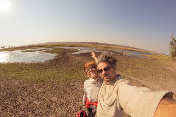 Casal tirando selfie em Chobe River, Namíbia Botswana fronteira, África. Vista de Fisheye de cima, imagem tonificada. Chobe National Park, famosa reserva de vida selvagem e destino de viagem de luxo . — Fotografia de Stock