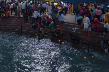 Haridwar, Hindistan - 20 Mart 2017: Haridwar, Hindistan 'da kutsal ghat, Hindu dini için kutsal kasaba. Hacılar Ganj Nehri 'ne çiçekler ve yanan mumlar sunuyor..