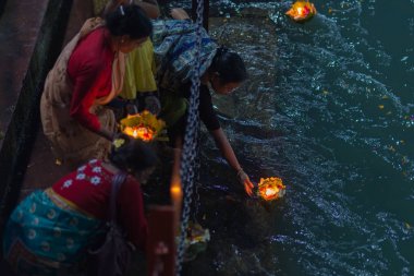 Haridwar, Hindistan - 20 Mart 2017: Haridwar, Hindistan 'da kutsal ghat, Hindu dini için kutsal kasaba. Hacılar Ganj Nehri 'ne çiçekler ve yanan mumlar sunuyor..