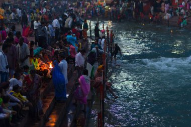 Haridwar, Hindistan - 20 Mart 2017: Haridwar, Hindistan 'da kutsal ghat, Hindu dini için kutsal kasaba. Hacılar Ganj Nehri 'ne çiçekler ve yanan mumlar sunuyor..