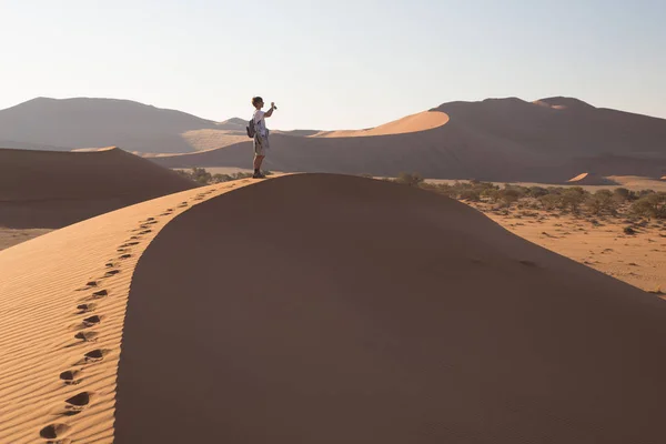 Tourist walking on the scenic dunes of Sossusvlei, Namib desert, Namib Naukluft National Park, Namibia. Adventure and exploration in Africa. — Stock Photo, Image