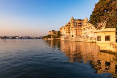 Gün batımında Udaipur cityscape. Göl PICHOLA, seyahat hedef, Rajasthan Hindistan görkemli şehir sarayının
