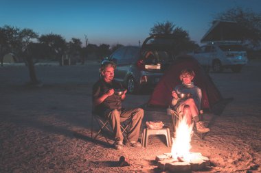 Gece kamp sitedeki yetişkin çift rahatlatıcı. Macera National Park, Güney Afrika. Yanan kamp ateşi ve çadır içinde belgili tanımlık geçmiş. Tonlu görüntü.