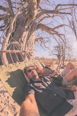 Hamak büyük Baobab Afrika savana Ağaçta asılı üzerinde çift alarak selfie. Tonlu görüntü, balıkgözü görüntüleyin. Vahşi safari ve Afrika macera.