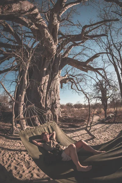 Hamak büyük Baobab Afrika savana Ağaçta asılı üzerinde çift alarak selfie. Tonlu görüntü, balıkgözü görüntüleyin. Vahşi safari ve Afrika macera. — Stok fotoğraf