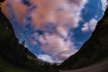 Yıldızlı gökyüzü bulanık hareket renkli bulutlar ve parlak ay ışığı ile. Avrupa Alps, balıkgözü ultra geniş görüş için geniş gece manzarası.
