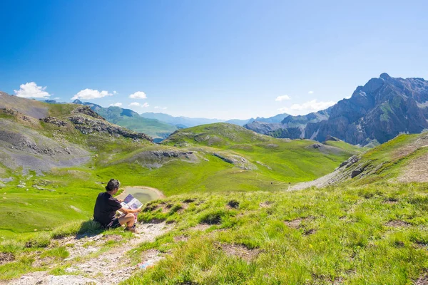 Hiker reading trekking map while resting at panoramic mountain spot. Outdoors activities, summer adventures and exploration on the Italian French Alps. Expansive view from the top. — Stock Photo, Image
