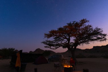 Yıldızlı gökyüzü gece kamp sitesi. Milli Parkı, Afrika macera. Kamp ateşi ve çadır büyük akasya ağacı ile yazma.