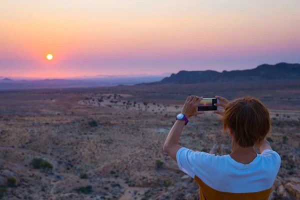 旅游与智能手机拍摄壮丽景色的荒芜山谷中纳米布沙漠，在非洲的纳米比亚，雄伟的旅游景点。色彩斑斓的天空，在地平线上. — 图库照片
