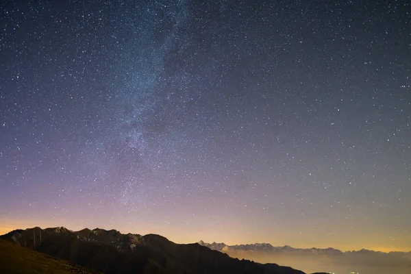 El maravilloso cielo estrellado en Navidad y la majestuosa alta cordillera de los Alpes franceses italianos, con pueblos brillantes debajo y la luz de la luna . — Foto de Stock