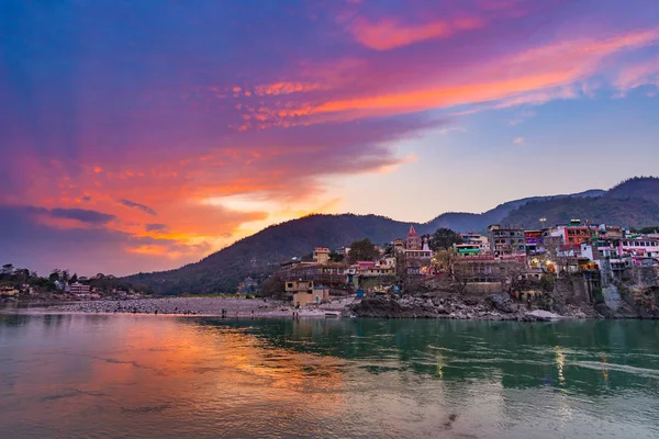 Hora do anoitecer em Rishikesh, cidade sagrada e destino de viagem na Índia. Céu colorido e nuvens refletindo sobre o rio Ganges . — Fotografia de Stock