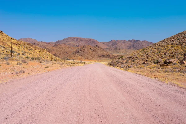 Gravel 4x4 road crossing the colorful desert at Twyfelfontein, in the majestic Damaraland Brandberg, scenic travel destination in Namibia, Africa. — Stock Photo, Image