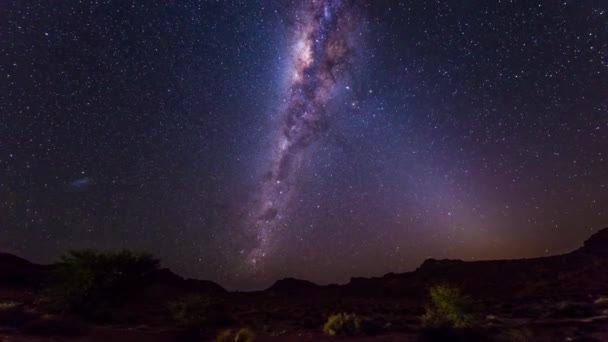 A aparente rotação de uma extraordinária Via Láctea brilhante e céu estrelado além das montanhas do deserto da Namíbia, Namíbia. Tempo de Caducidade . — Vídeo de Stock