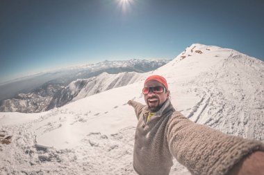 Açık mavi gökyüzü ile güzel İtalyan Alpleri'nde karlı yamaç selfie alarak yetişkin alpin kayakçı sakal, güneş gözlüğü ve şapka, ile. Tonlu görüntü, vintage tarzı, ultrawide açı balıkgözü lens.