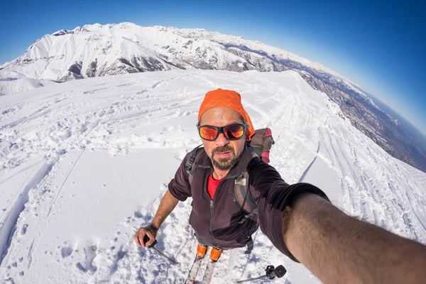 Pro dospělé alpin lyžař plnovous, sluneční brýle a klobouk, přičemž selfie na zasněženém svahu v krásné Italské Alpy s jasnou modrou oblohu. Tónovaný obrázek, vintage styl, širokém pozorovacím úhlu fisheye objektivu. — Stock fotografie