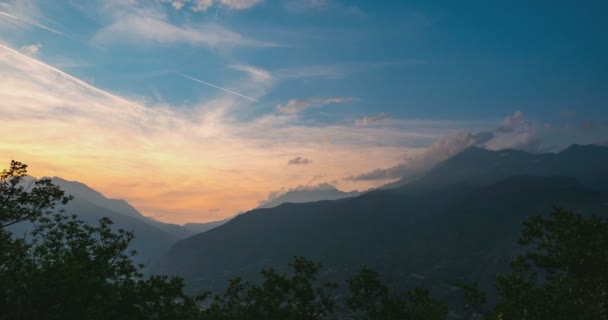 Montañas nevadas y picos con nubes en movimiento sobre los Alpes en verano, provincia de Torino, Italia. El lapso de tiempo se desvanece de la luz del sol al atardecer. Carretera sinuosa que conduce al paso de montaña . — Vídeos de Stock