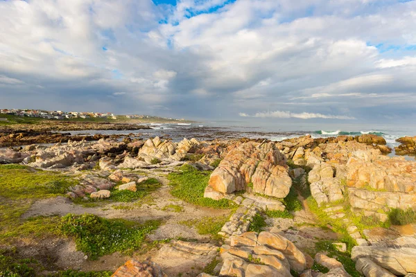 Klippiga kustlinje på havet på De Kelders, Sydafrika, känd för valskådning. Vintersäsongen, molnigt och dramatisk himmel. — Stockfoto