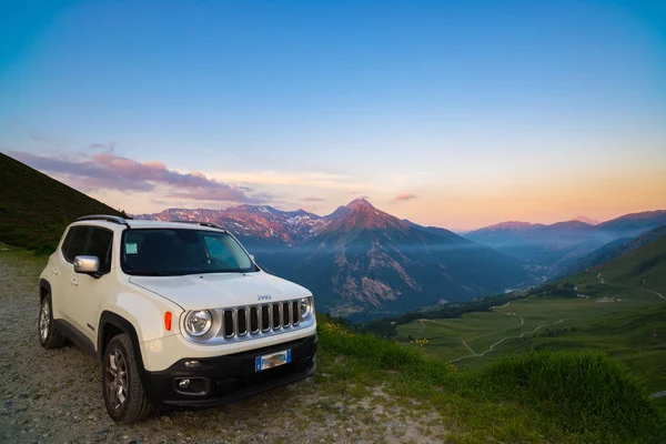 Beyaz Jeep Renegade yukarıdan İtalyan Alpleri panoramik noktasında toprak yol üzerinde park etmiş. Gün batımında, Kurtlar Vadisi buğu renkli gökyüzü.