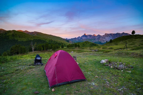 Acampar com tenda a alta altitude nos Alpes. Snowcapped gama montesa e cénico céu colorido ao pôr do sol. Aventura e exploração no verão . — Fotografia de Stock